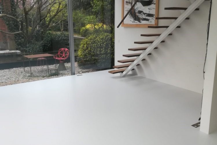 White resin floor in a contemporary interior with a suspended staircase in Brussels